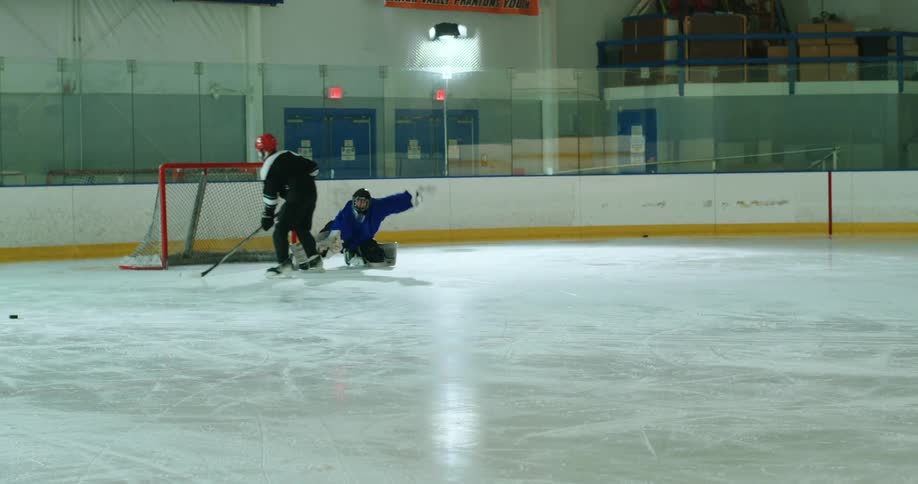 A goalkeeper defending a hockey forward who scores a goal
