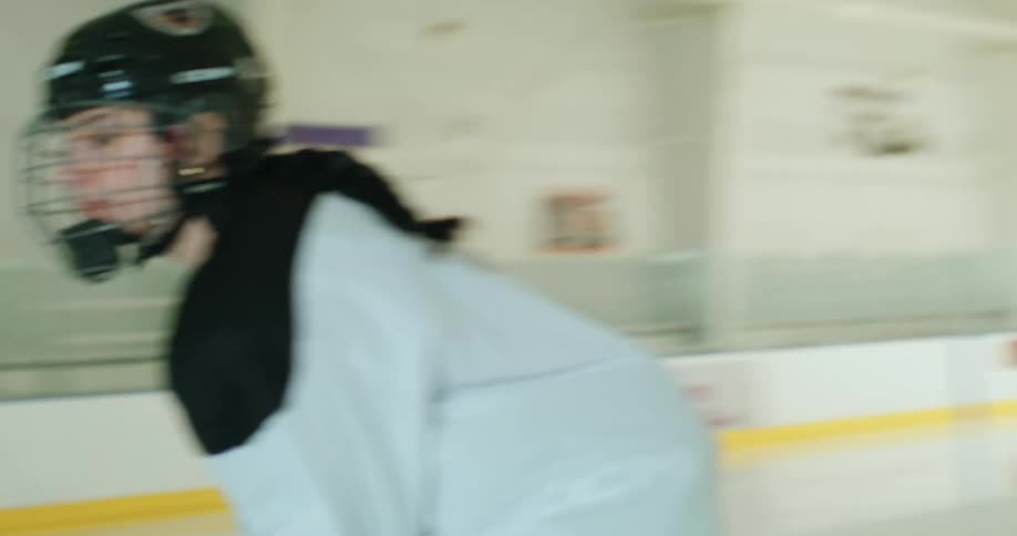 A hockey player drives the puck on the rink