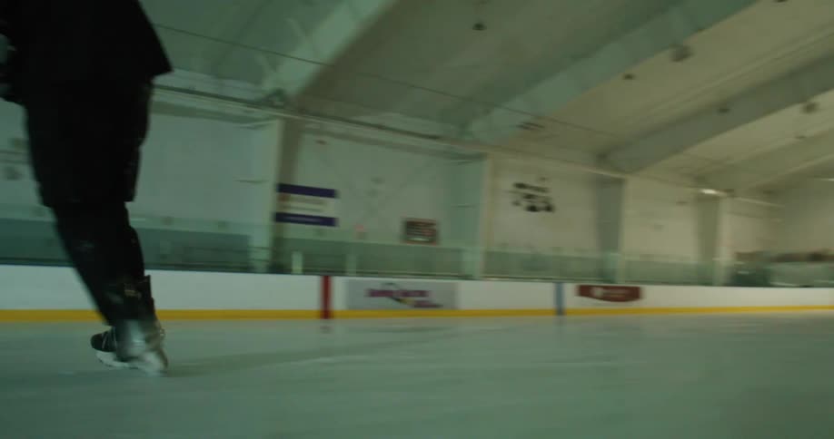 A hockey player skating on an ice rink and guiding the puck using his stick