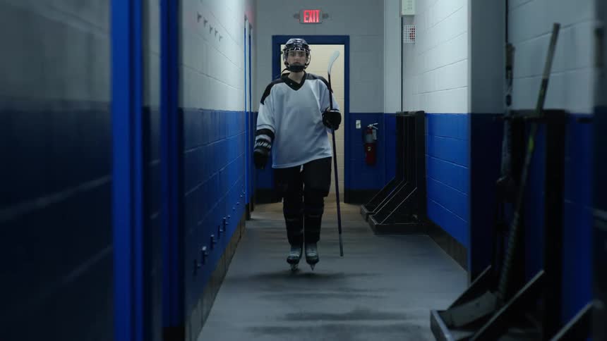 Female hockey player leaving her hockey equipment on a wall and entering the locker room
