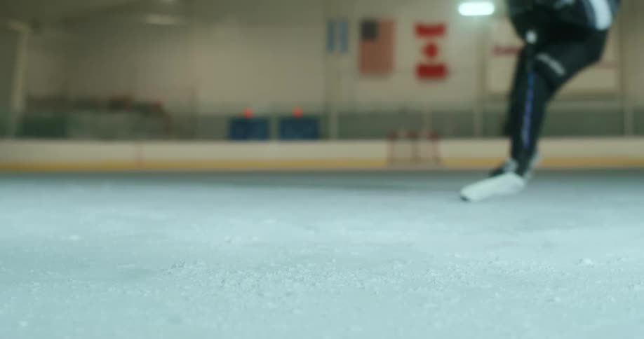 Hockey player's feet in skates sliding on ice with a hockey stick