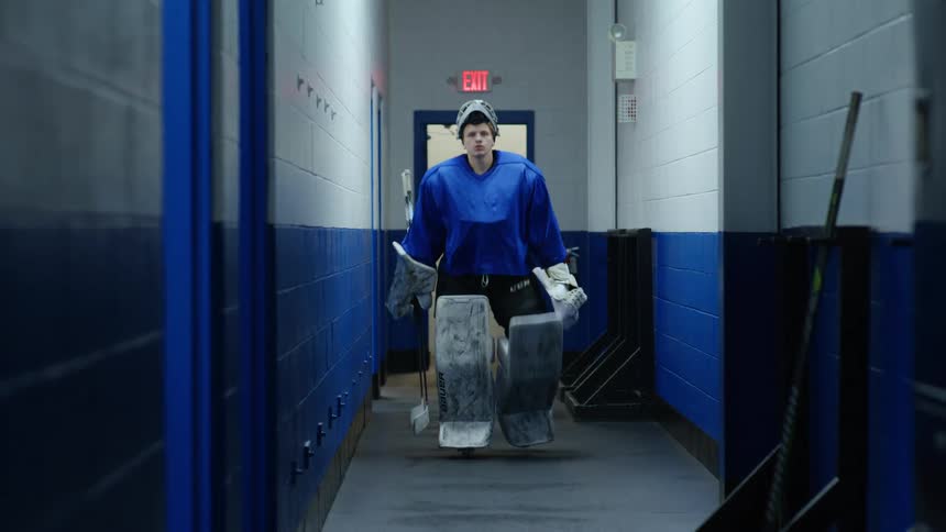 A hockey player walks down the hall and enters a room
