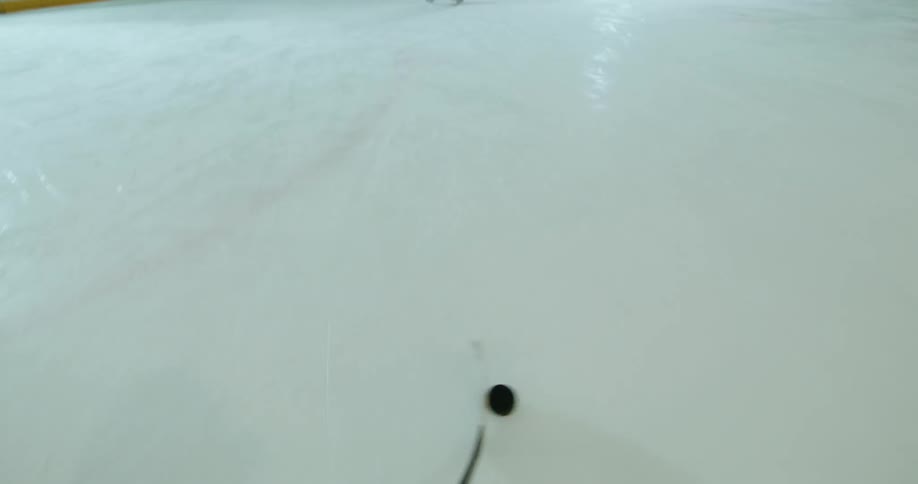 Point of view of a person with a stick handling a small black ball and shooting it at the goalkeeper in a hockey practice