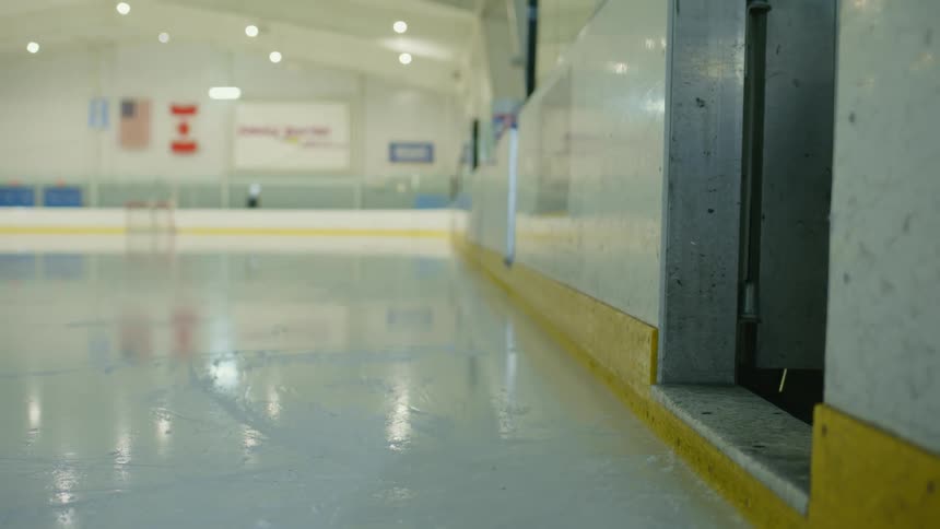 Player with their stick entering a hockey ice rink