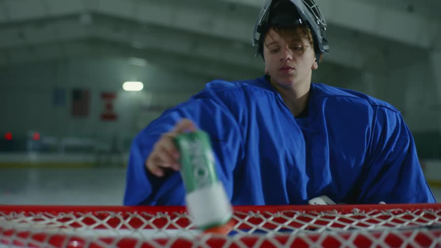 A hockey player drinks water near the net