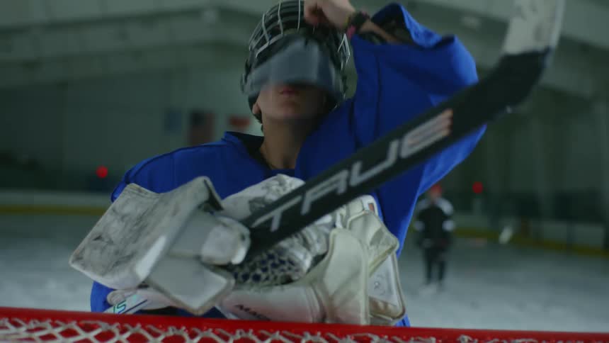 A fully equipped goalie prepares in front of the net on an ice hockey rink