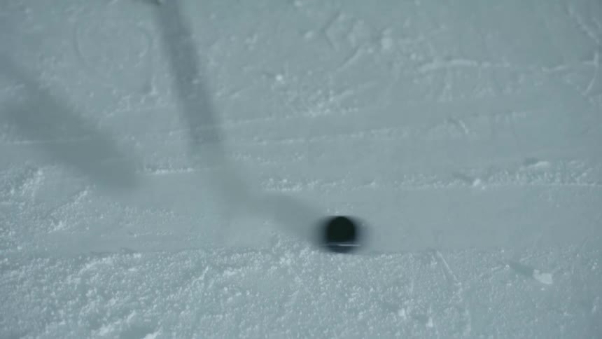 Close up of a puck being moved with a stick on an ice skating rink