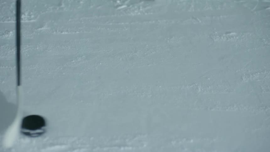 A hockey stick handling the puck on the ice