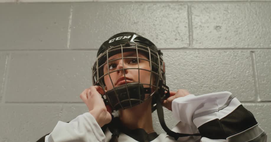 Woman putting on hockey sport protective helmet