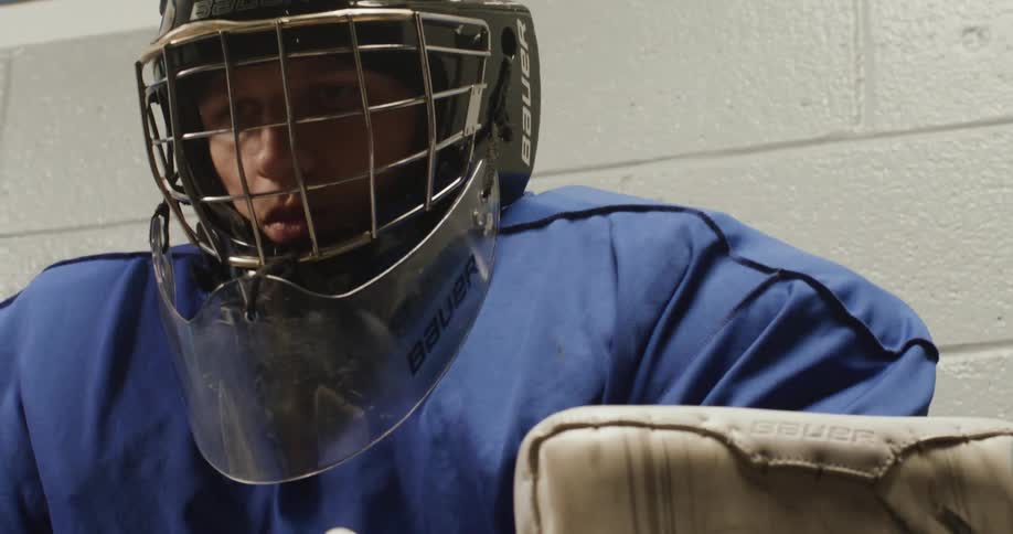 An ice hockey goalie adjusting protective gear