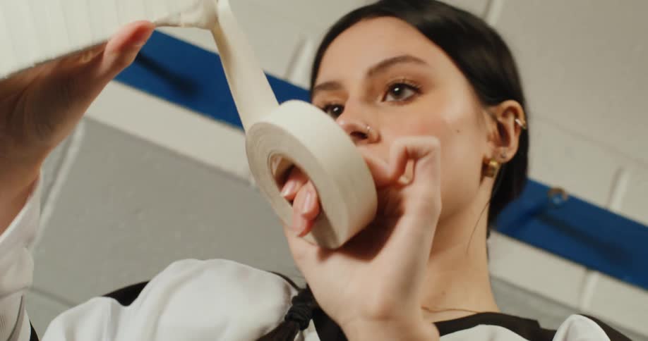 Woman putting white tape on sports hockey stick