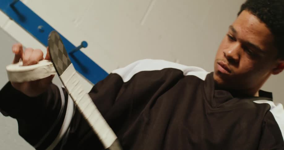 Male hockey player concentrates on wrapping hockey stick