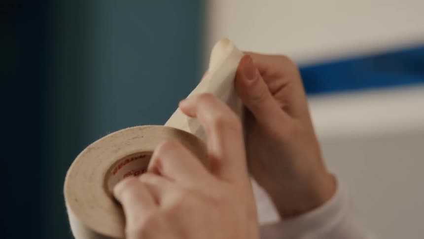 Close up of a person wrapping a hockey stick with tape