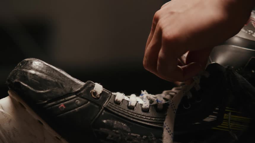 Close up of the hands of a person tying up the laces of ice skates