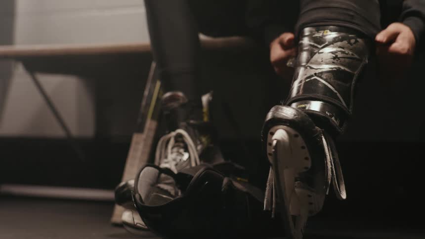 A hockey player is putting on their skates