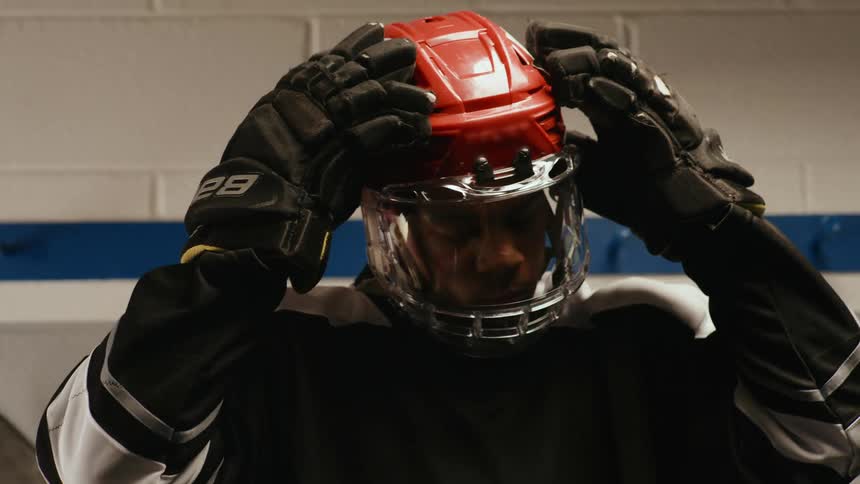 A hockey player adjusts a helmet with a full face shield visor