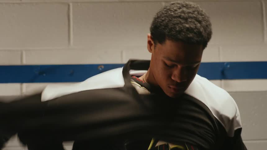 Man in a locker room putting on his hockey jersey
