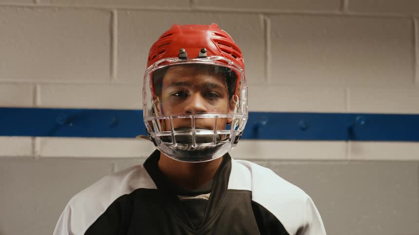 A young man wearing an orange red hockey helmet