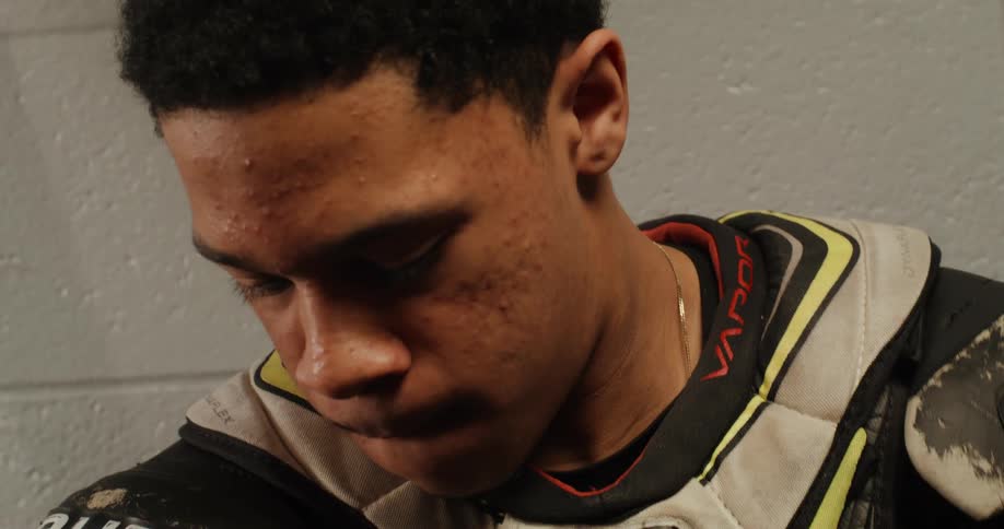 A clip of a young black male hockey player putting on his gear