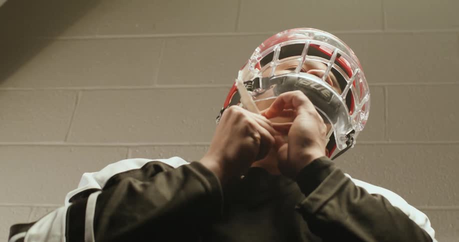 A hockey player adjusting a helmet with a full face shield visor