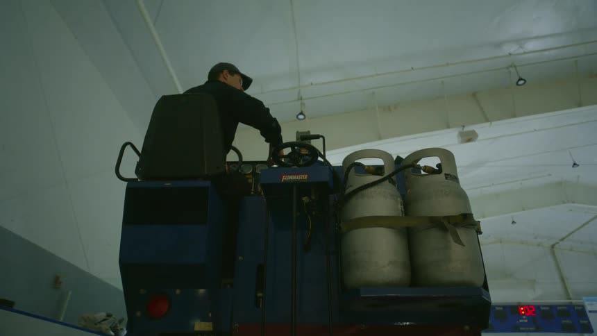 View from behind of a man driving a zamboni