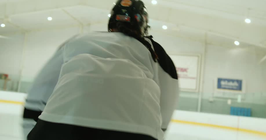 Female hockey player skates down ice rink