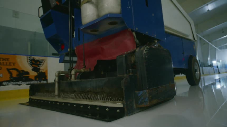 A zamboni drives over a hockey ice rink
