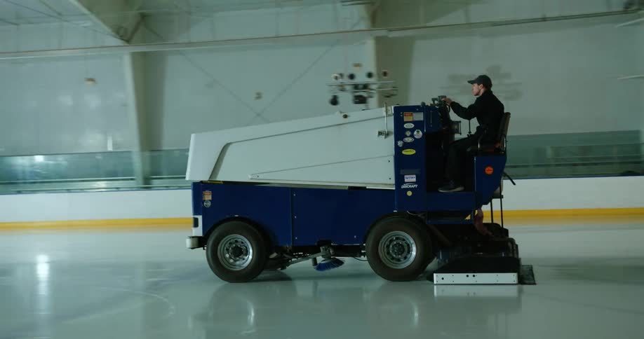 A man driving a zamboni ice truck on an ice rink