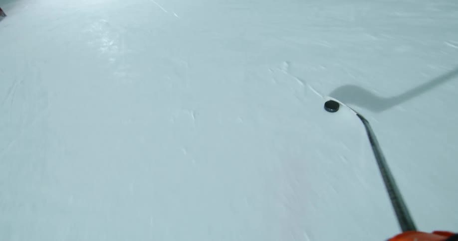 A hockey player shoots a puck into a net on an ice rink