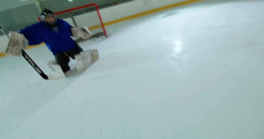 A hockey player scores a goal by shooting a puck past the goalie