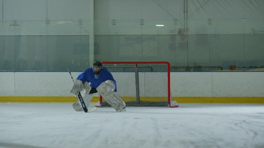 Goalie blocks shot taken by hockey player during game
