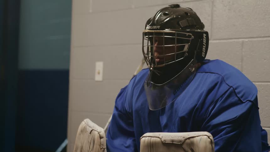 A hockey goalie in a locker room preparing for the game ahead with focus and determination