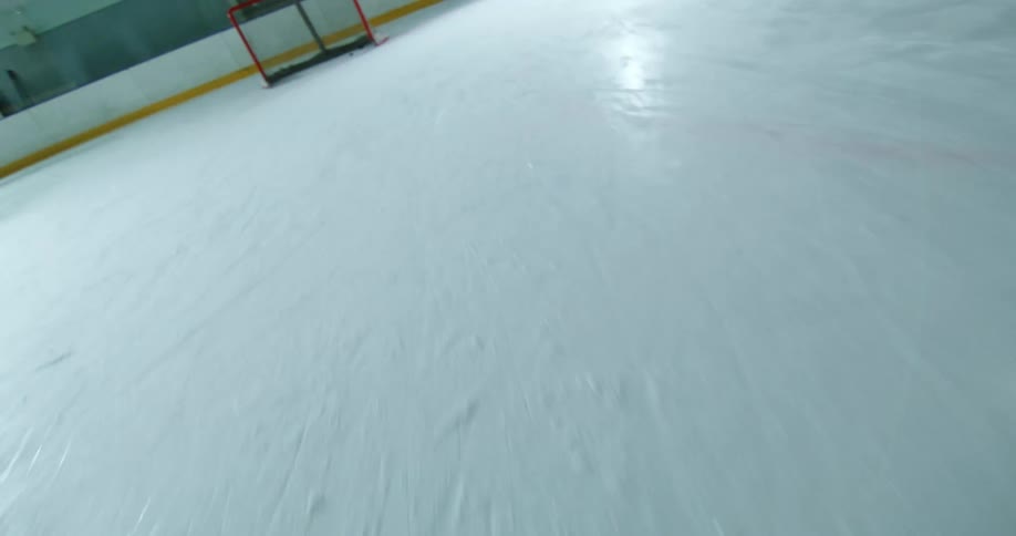 A hockey player swings their stick to hit the puck across the ice