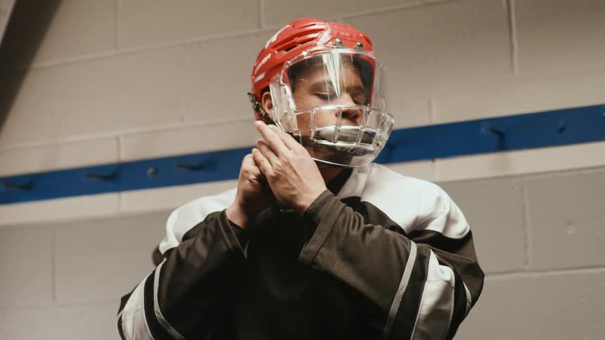 Male hockey player putting on his helmet