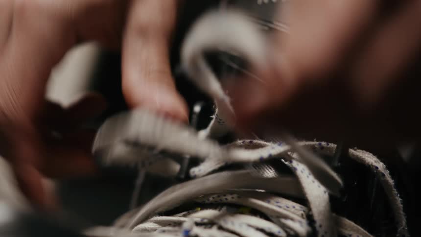 Closeup of a mans hands tying his ice skate laces