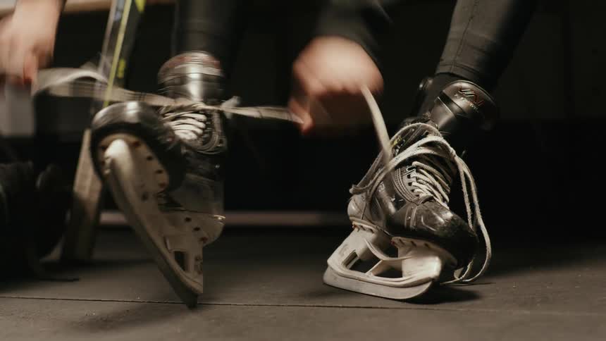 Closeup of a man's hands tying the laces of his ice skates