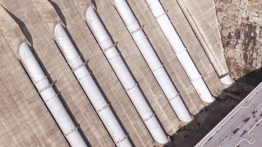 An aerial view of huge white pipes of a concrete dam