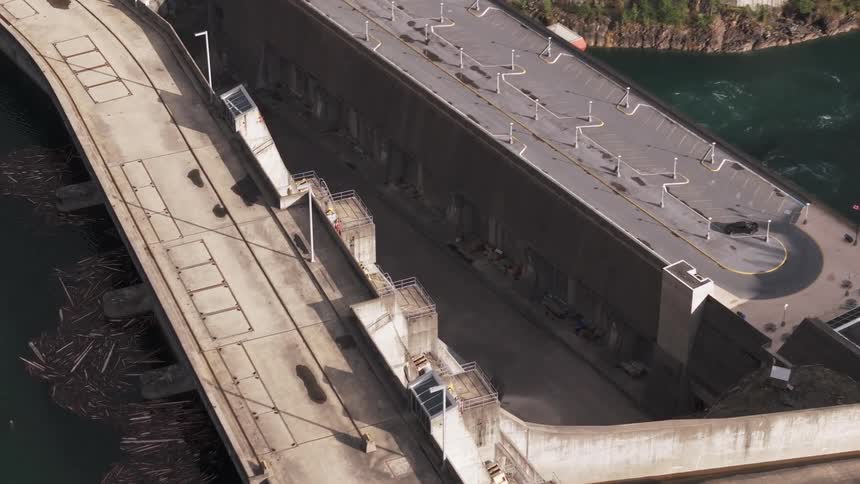Aerial view of a hydro dam with a concrete structure equipped with several gates and flanked by water