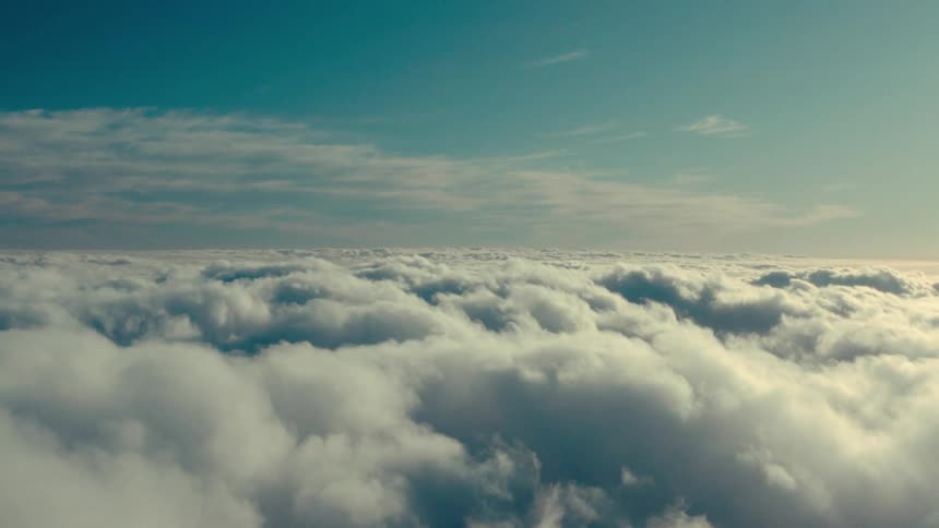 An aerial view of several white clouds at the bottom in contrast to the blue sky