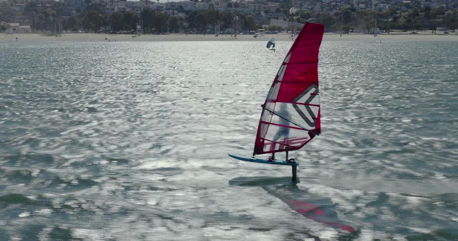 A windsurf racer flies across the water at sunset