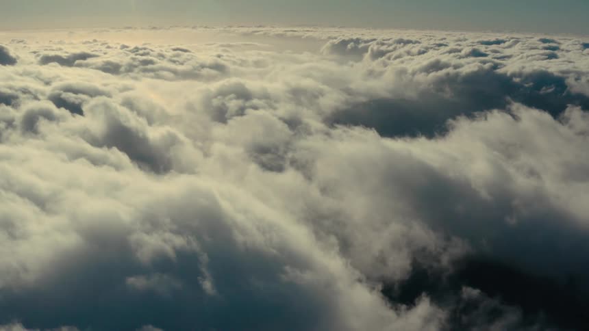 A view above the clouds of several white clouds in a clear sky
