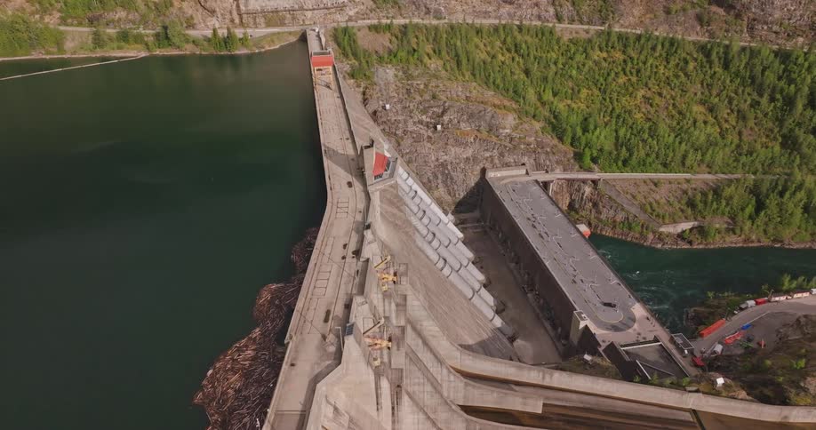 Forested slope towers over dam separating lake from river