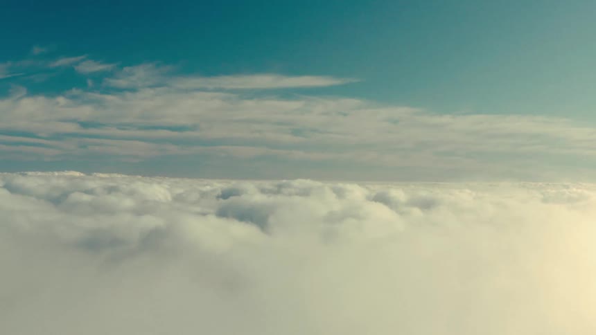 An aerial view above the white clouds of the blue sky