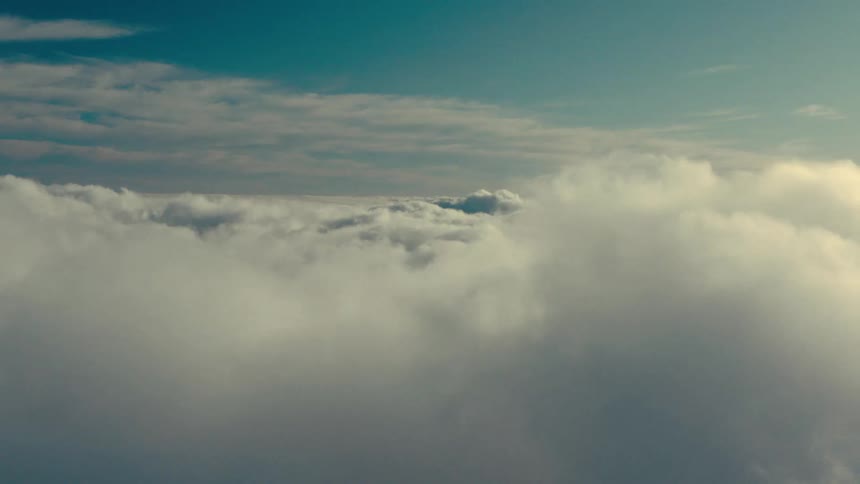 The fluffy clouds in the airplane window create a dreamy seascape above the world