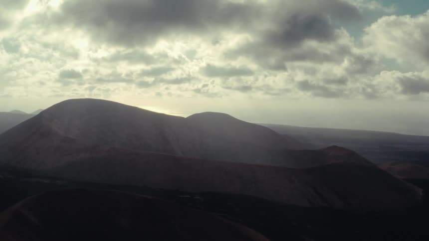 A volcanic landscape under cloud covered sky at noon