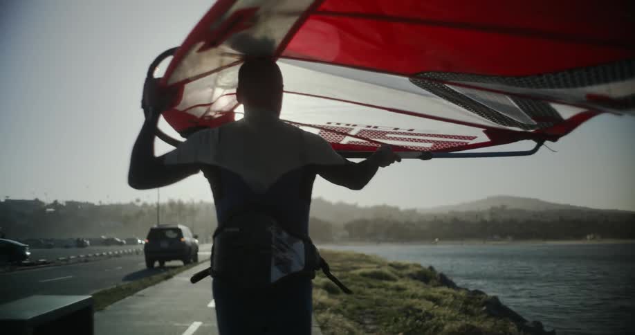 An Olympic windsurfer carries his gear to the water