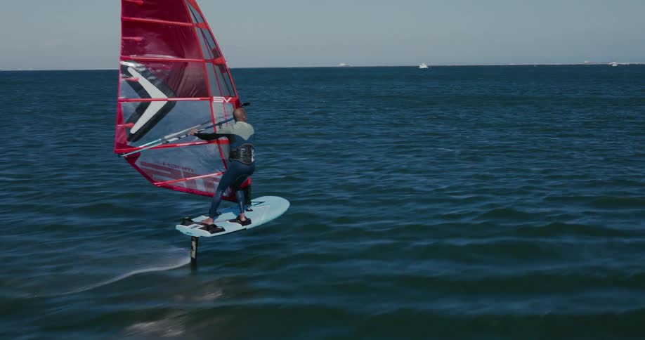 A hydrofoil windsurfer races across the water