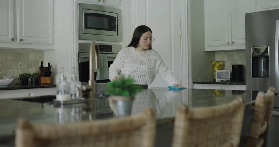 A woman is cleaning the counter in the kitchen