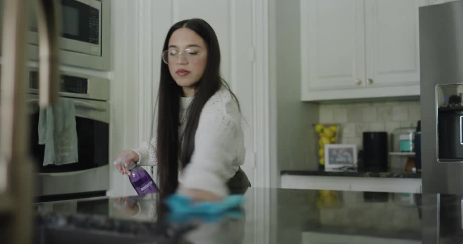 A woman cleans a kitchen countertop