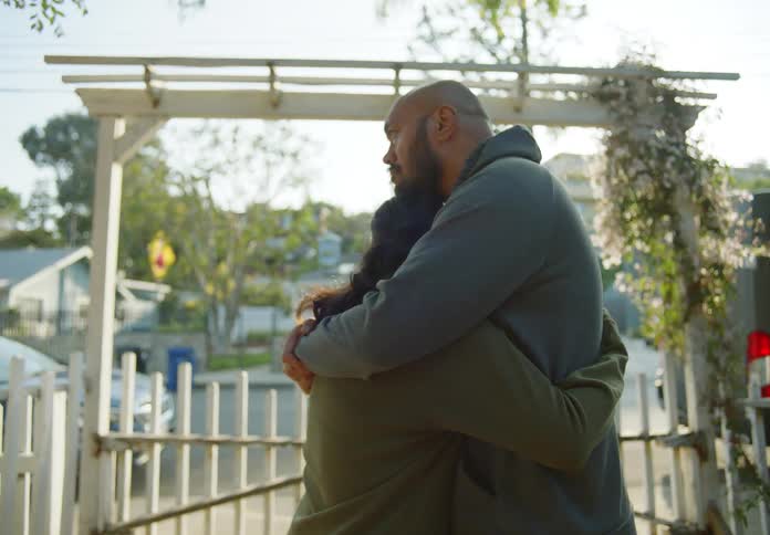 A man and woman hug in the yard